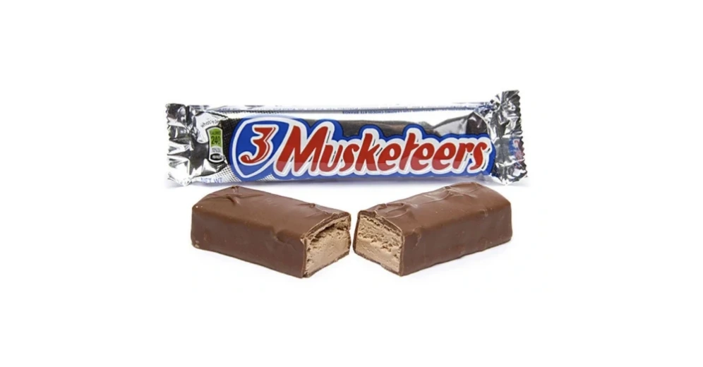 A 3 Musketeers chocolate bar, broken in half to show the inside of the bar, with it's packaging in the background