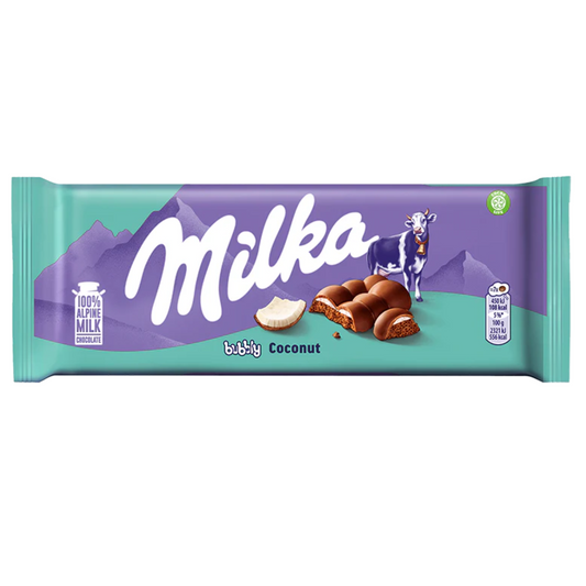 Milka chocolate bar packaging with a green background and purple mountains design, showcasing the chocolate bar with a piece of coconut. A cow is also pictured.