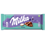 Milka chocolate bar packaging with a  green background and purple mountains design, showcasing the chocolate bar with a piece of coconut. A cow is also pictured.
